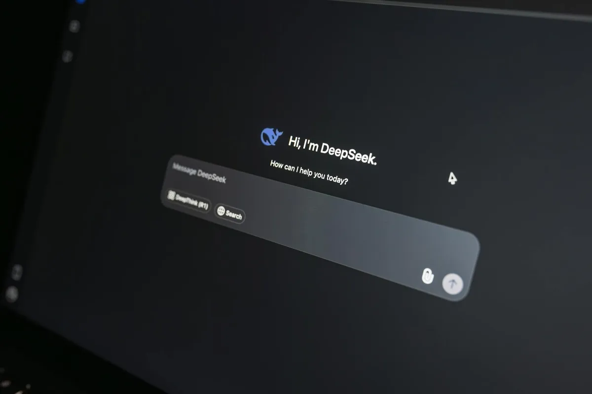 A laptop on a clean desk with an AI chatbot interface visible on the screen